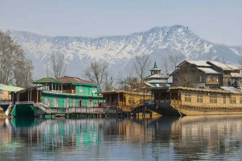 Houseboats on a lake below snow-covered mountains