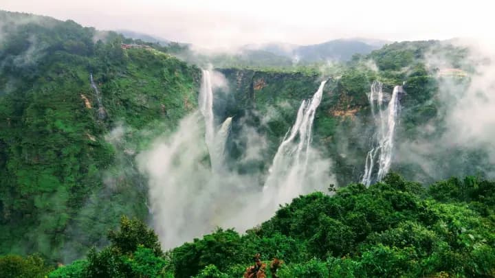 Several waterfalls falling over a green cliff